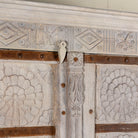 Close up image of a old door cabinet with reclaimed teak doors, floral carvings, and iron accents; artisan teak wood wardrobe with mango wood frame, 100 × 44 × 206 cm.