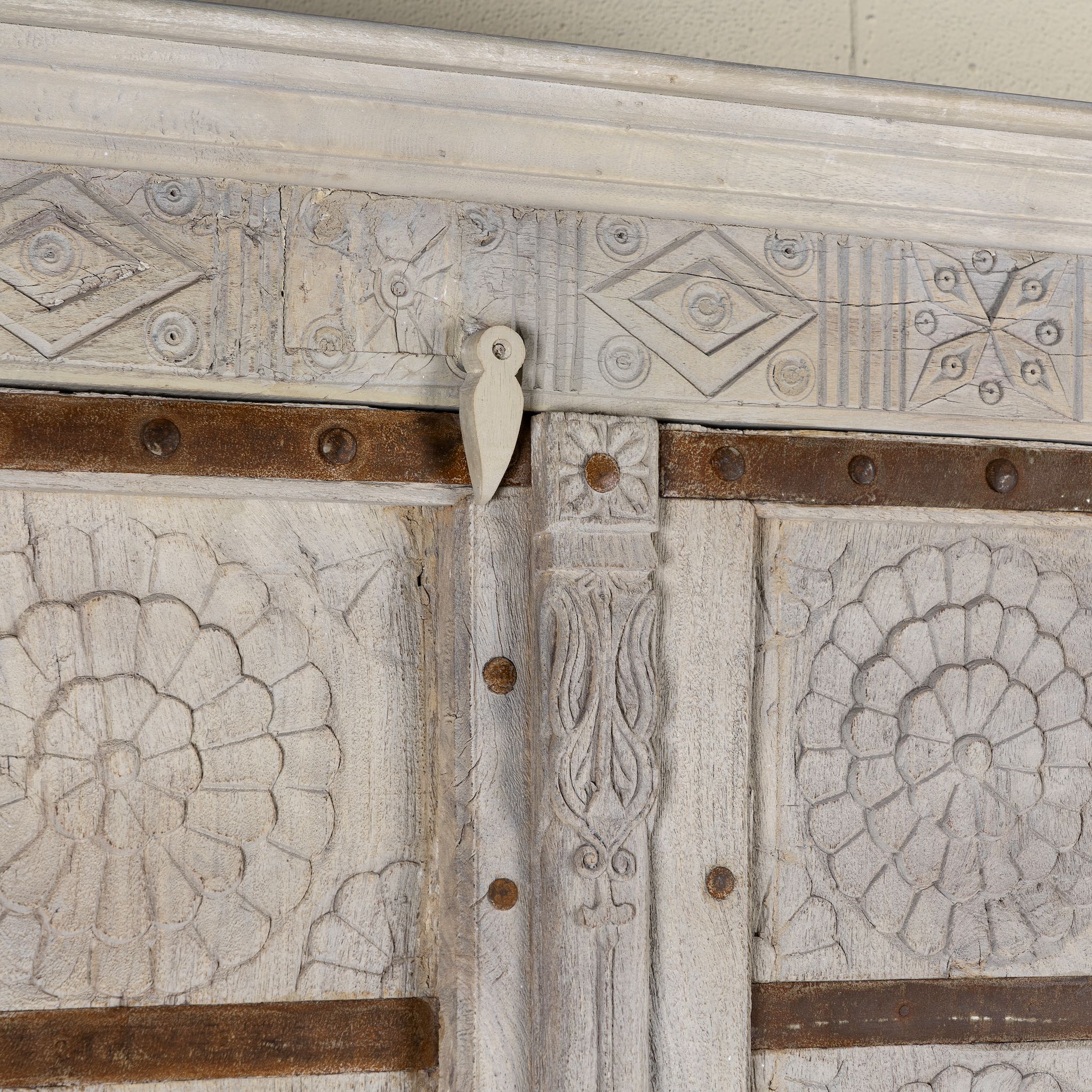 Close up image of a old door cabinet with reclaimed teak doors, floral carvings, and iron accents; artisan teak wood wardrobe with mango wood frame, 100 × 44 × 206 cm.