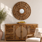 Lifestyle image of a of a round mango wood mirror Babra with concentric carved design and mirror inlays. A piece of unique wall decor combining artisanal craftsmanship and rustic bohemian charm.