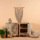 Open door image of a pair of mango wood bedside tables with hand-carved tree motifs and antique finish; perfect bedroom furniture and mango wood furniture, 50 × 70 × 40 cm.