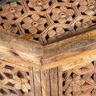 Close up image of a octagonal mango wood coffee table with intricate floral and geometric carvings; durable hand-carved coffee table, 90 × 90 × 46 cm.