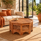 Lifestyle image of a Barkot octagonal mango wood coffee table with intricate floral and geometric carvings; durable hand-carved coffee table, 90 × 90 × 46 cm.