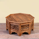 Side angle image of a Barkot octagonal mango wood coffee table with intricate floral and geometric carvings; durable hand-carved coffee table, 90 × 90 × 46 cm.