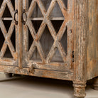Close up image of the leg part of a vintage display cabinet made from solid mango wood with glass doors and shelving – handcrafted Ibiza-style showcase with carved details.