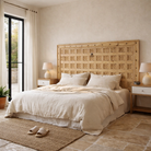 Lifestyle image of a Bheem hand-carved teak headboard made from an old Indian ceiling door, featuring floral panel carvings and a whitewashed finish—an authentic piece of old door headboards and old Indian door furniture.