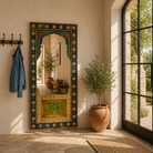 Lifestyle image of a painted mirror Bhuj with hand-carved floral design in vibrant colors, made from antique teak wood. A bold piece of unique Indian furniture with artistic and historic charm.