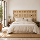 Lifestyle image of a Bhuvi hand-carved teak headboard made from an old Indian ceiling door, featuring symmetrical floral panels and a whitewashed finish—an heirloom-style piece of old door headboards and old Indian door furniture.