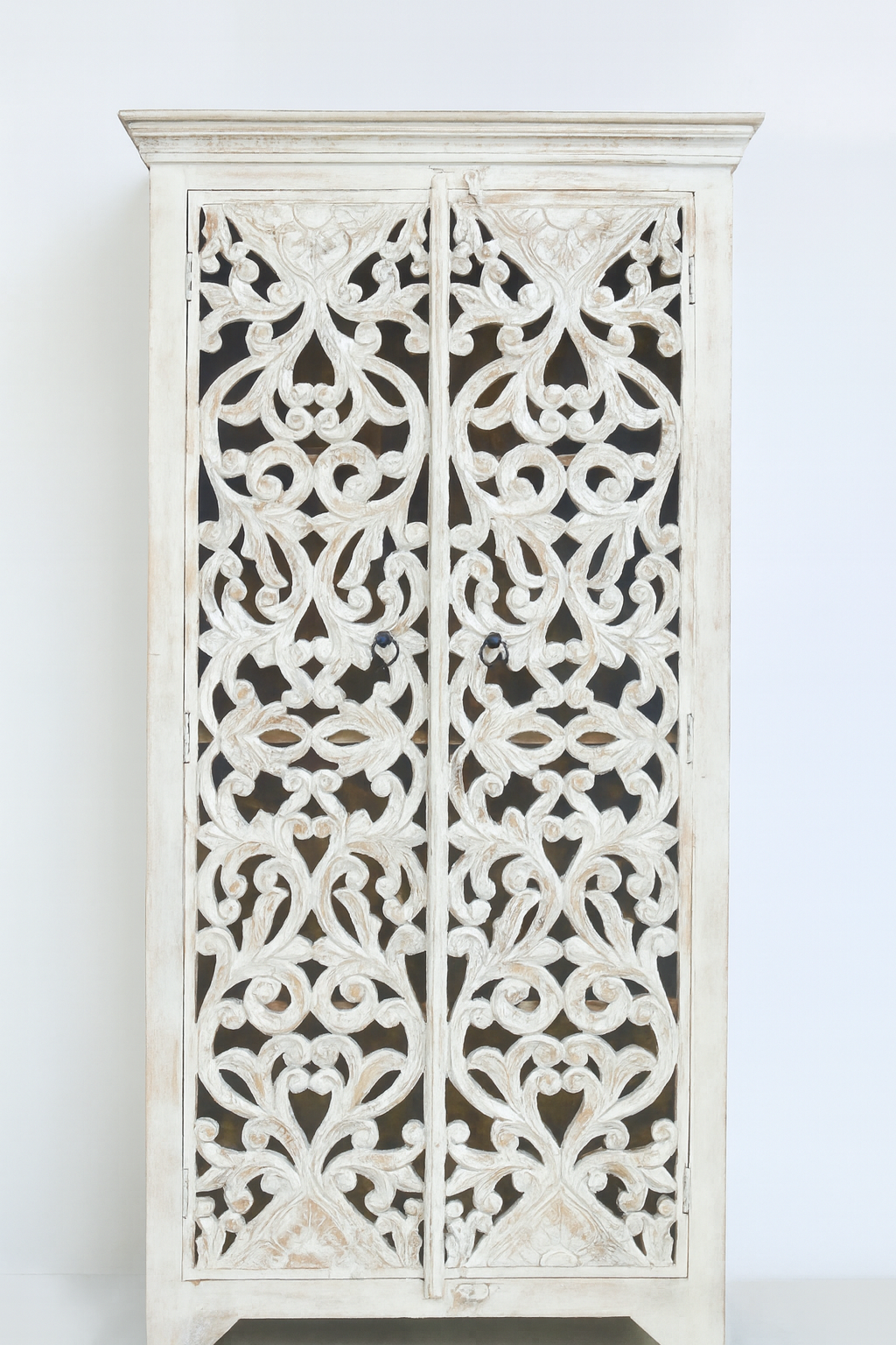 White background image of a hand-carved mango wood cabinet with floral and geometric motifs in white-washed finish – carved wooden furniture with Mediterranean-inspired design.