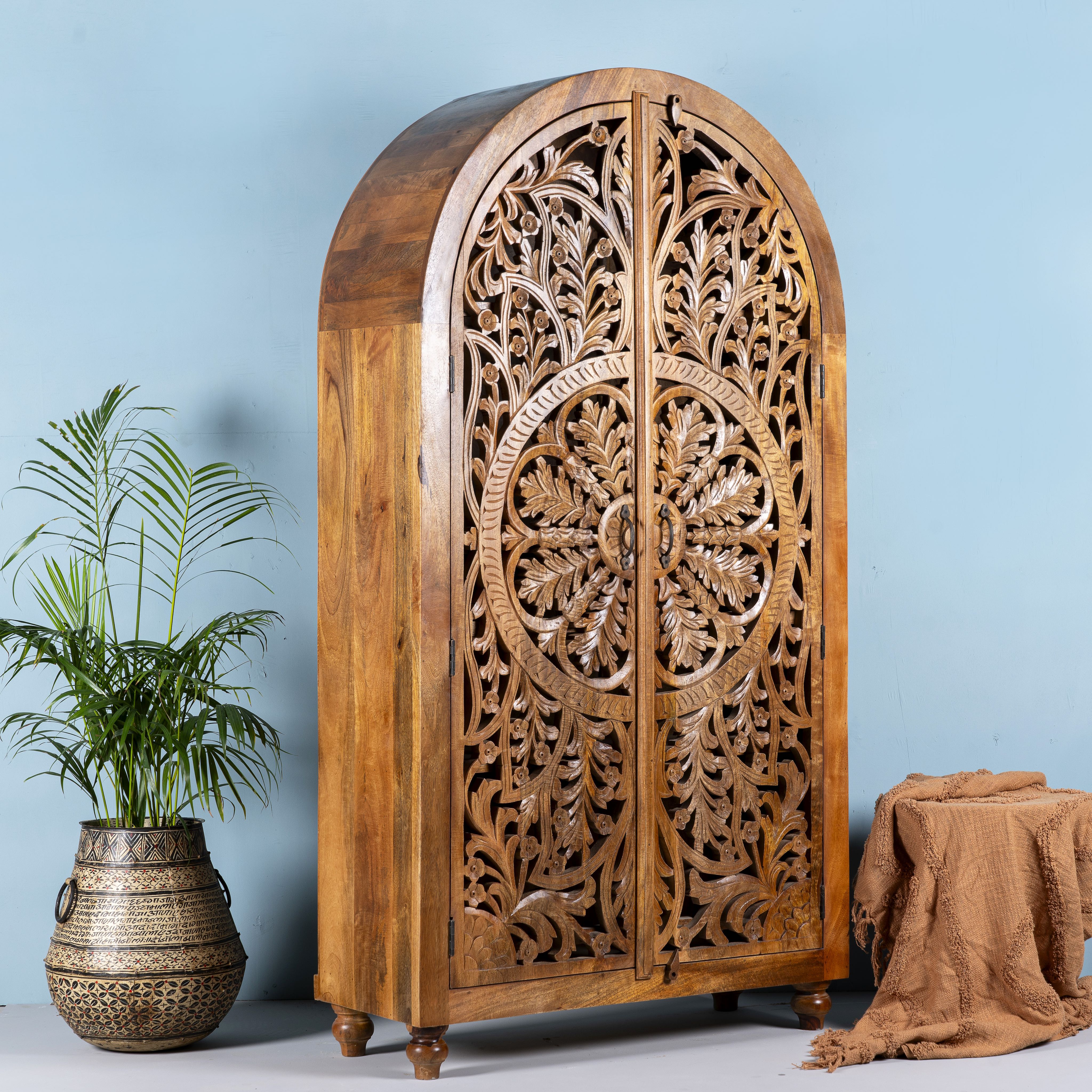 Side angle image of a unique wooden wardrobe made from solid mango wood with hand-carved floral design and rounded shape, 100 × 40 × 190 cm.
