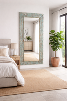 Lifestyle imagination of a carved mango wood mirror Apsara blue in distressed turquoise finish with intricate hand‑carved floral details. A unique piece of Indian furniture online ideal for vintage home decor and boho interiors.
