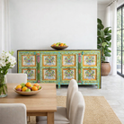 Lifestyle image of a of a reclaimed wood sideboard with hand painted floral motifs and distressed finish; artisanal storage furniture for bohemian interiors, 170 × 40 × 104 cm.