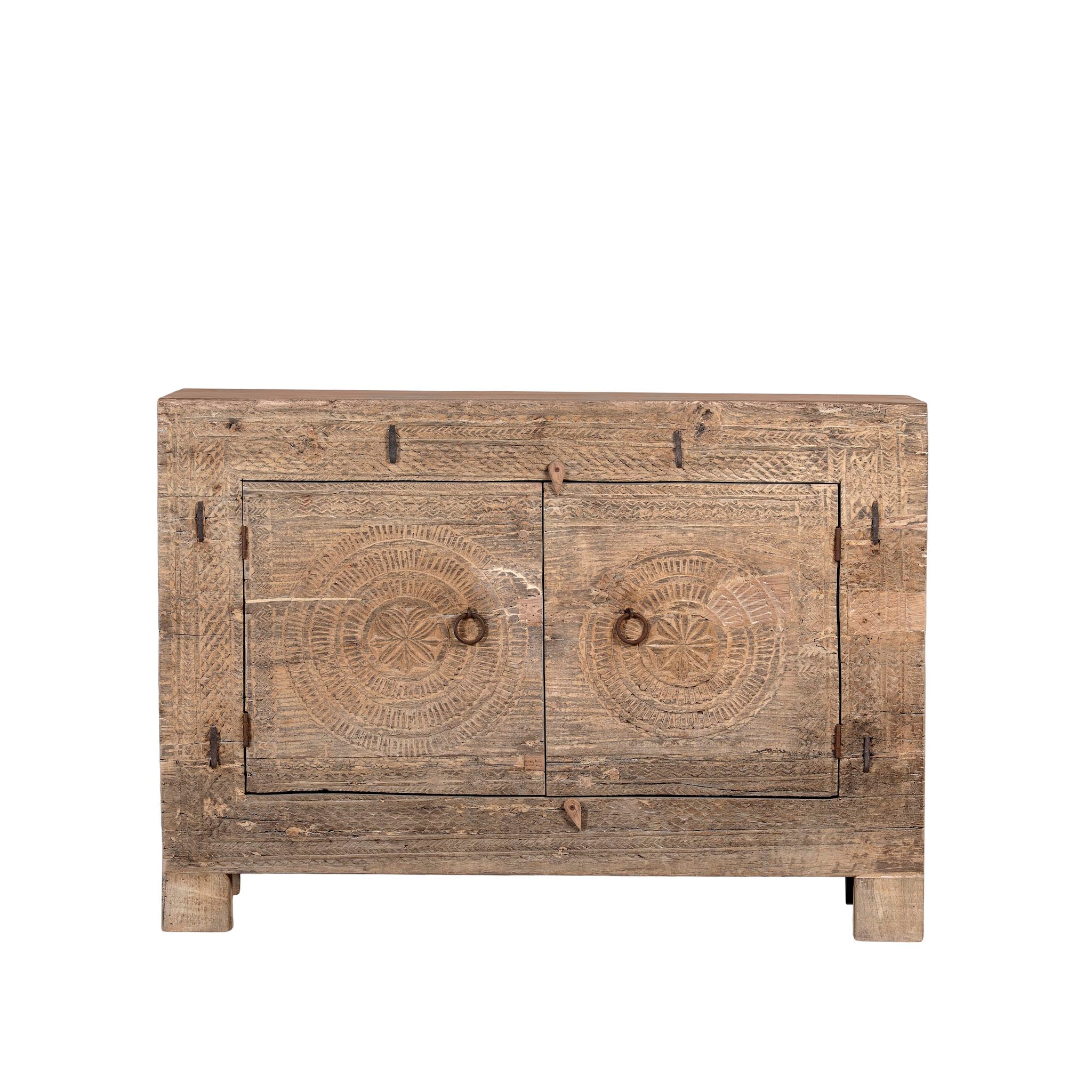 White background picture of a sideboard with hand-carved teak wood front, sandblasted for a sun-worn finish- a unique piece in rustic Ibiza style with circular mandala carvings and iron ring handles.