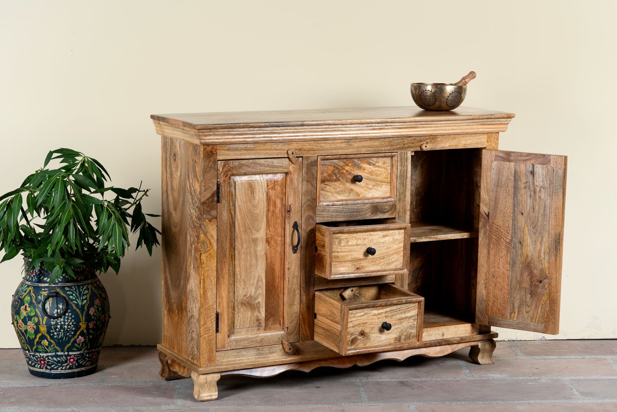 Side angle image with open doors of a sideboard made of natural mango wood with 2 doors, 4 compartments and 2 drawers. 