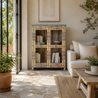 Lifestyle image of a Chaitanya hand-painted reclaimed wood display cabinet with colourful floral design 112cm