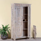 Side angle image with open door of a hand carved mango wood wardrobe in floral design with ample storage in ibiza style.
