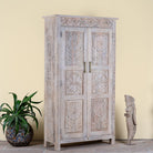 Side angle image of a hand carved mango wood wardrobe in floral design with ample storage in ibiza style.