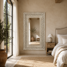 Lifestyle image of a tall white washed wall mirror with hand carved wooden mango wood frame; 180 × 90 × 10 cm.