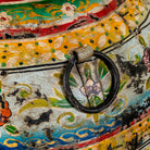Decorative object with floral patterns and a metal ring on a colorful background