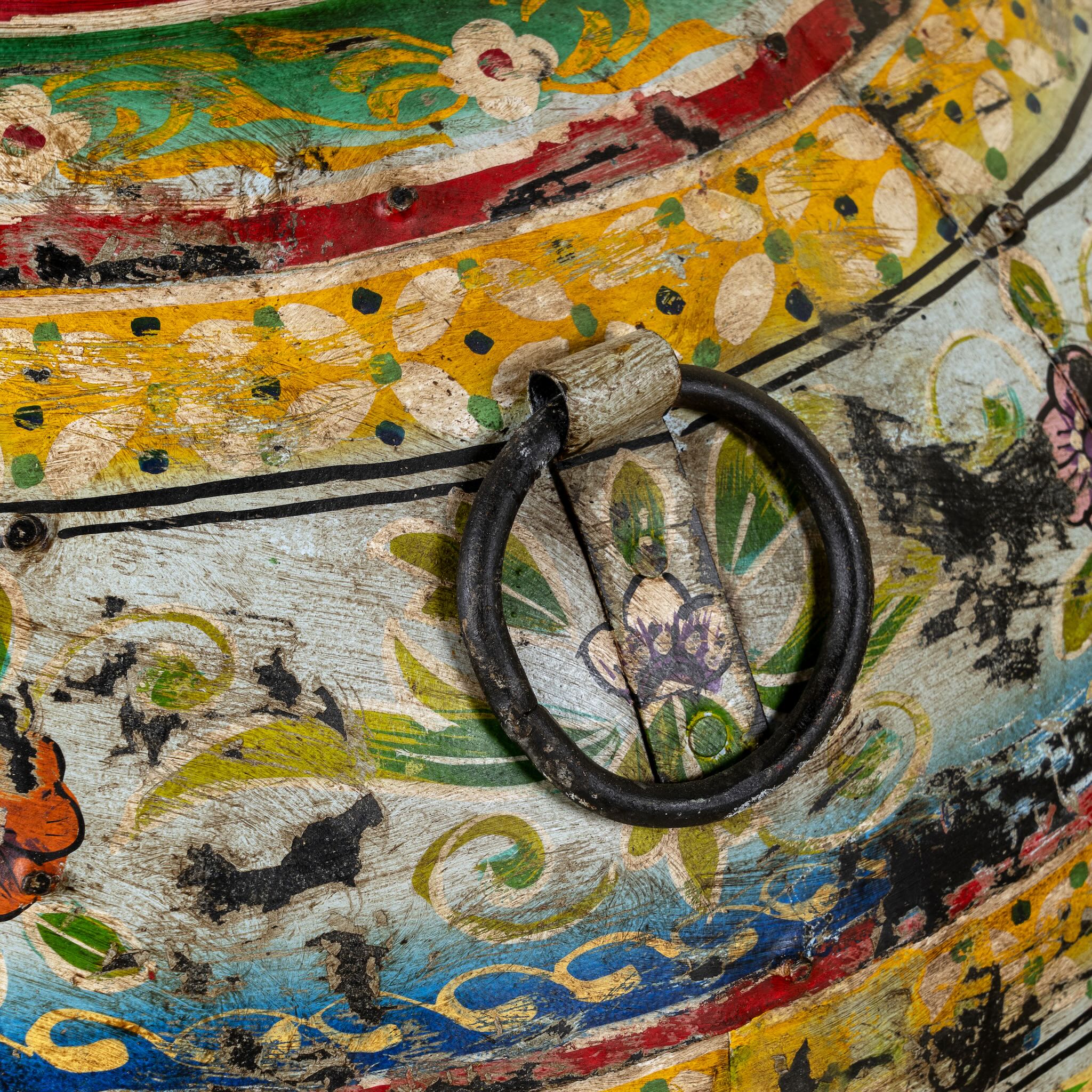 Decorative object with floral patterns and a metal ring on a colorful background