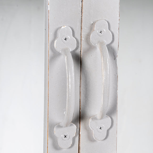 Close up image of a shabby chic teak wood cabinet with glass doors and five compartments – sustainable living room furniture crafted from refurbished old teak with rustic white finish.