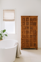 Lifestyle imagination of a hand-carved mango wood wardrobe with floral motifs; wooden wardrobe in natural finish, 100 × 45 × 190 cm.