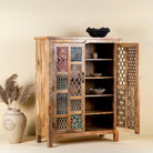 Side angle with open door image  of a artisanal mango wood cabinet with hand-carved floral and geometric lattice doors, distressed finish; ideal for boho style interiors, 100 × 45 × 130 cm.