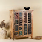 Side angle image of a artisanal mango wood cabinet with hand-carved floral and geometric lattice doors, distressed finish; ideal for boho style interiors, 100 × 45 × 130 cm.