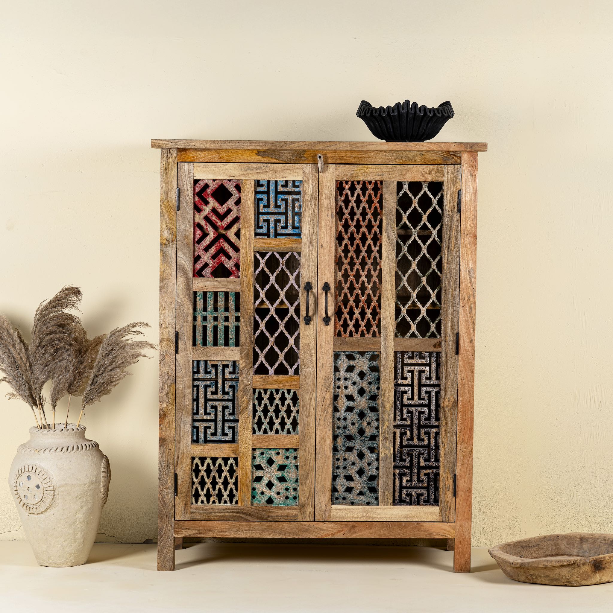 Artisanal mango wood cabinet with hand-carved floral and geometric lattice doors, distressed finish; ideal for boho style interiors, 100 × 45 × 130 cm.