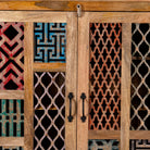 Close up image of a artisanal mango wood cabinet with hand-carved floral and geometric lattice doors, distressed finish; ideal for boho style interiors, 100 × 45 × 130 cm.