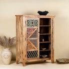 Side angle image with open door of a  handmade mango wood cabinet with carved floral and geometric lattice doors, distressed colour accents; artisanal furniture perfect for boho style interiors, 100 × 45 × 130 cm.