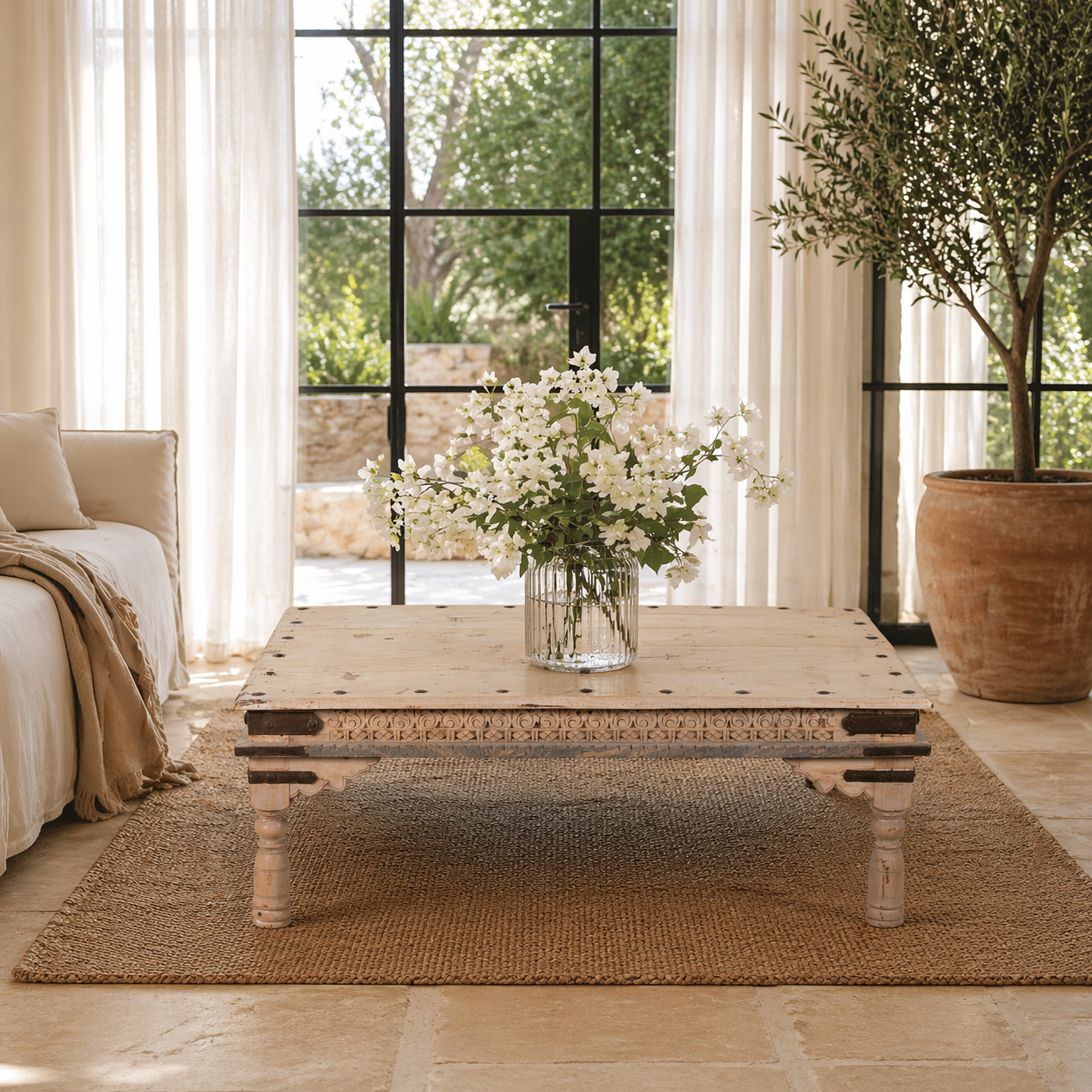 Lifestyle image of a Ibiza style coffee table teak wood, reclaimed teak with carved details; sustainable Indian coffee table, 122 × 77 × 44 cm.