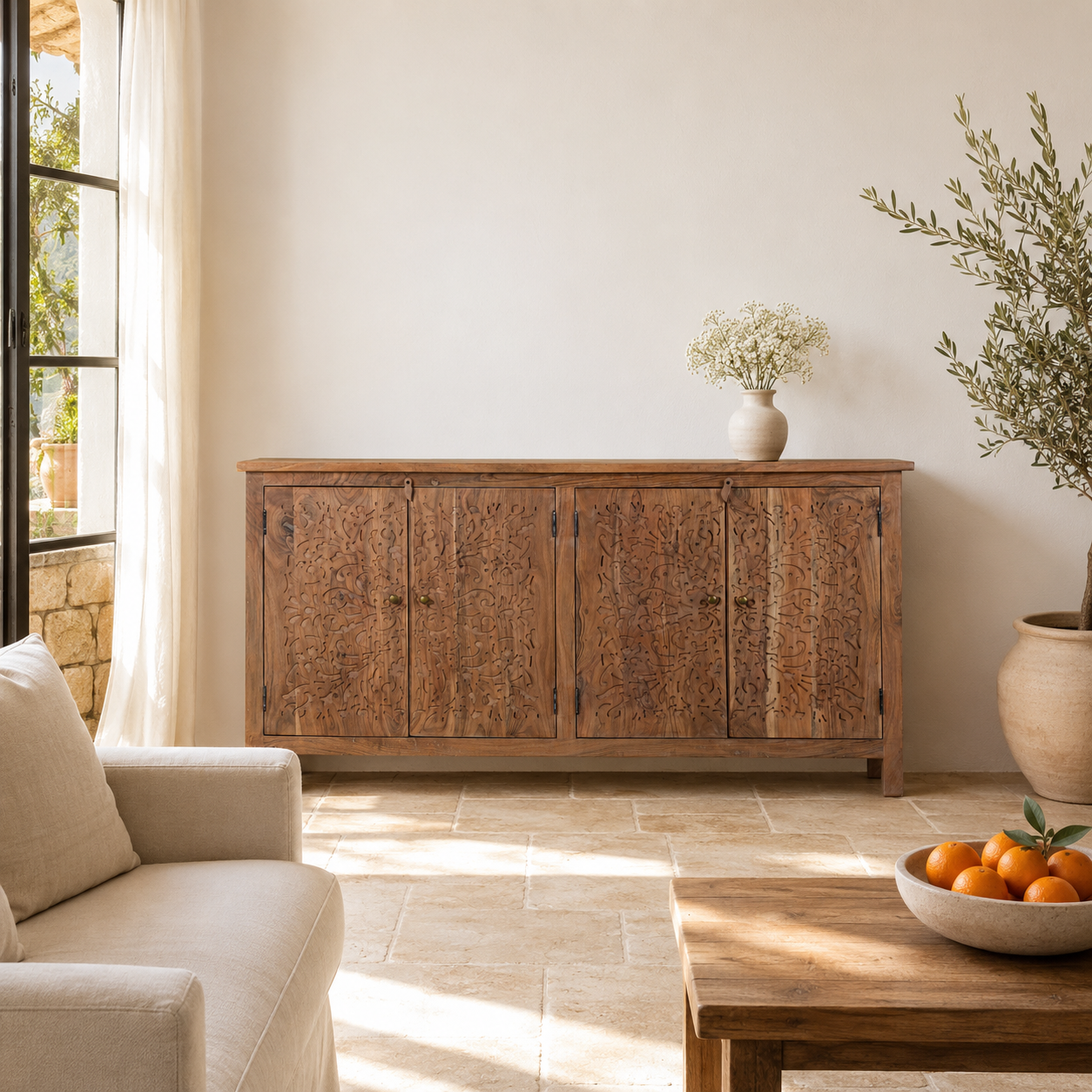 Lifestyle image of an acacia wood sideboard with floral carvings over all 4 doors and brass fitted door handles.
