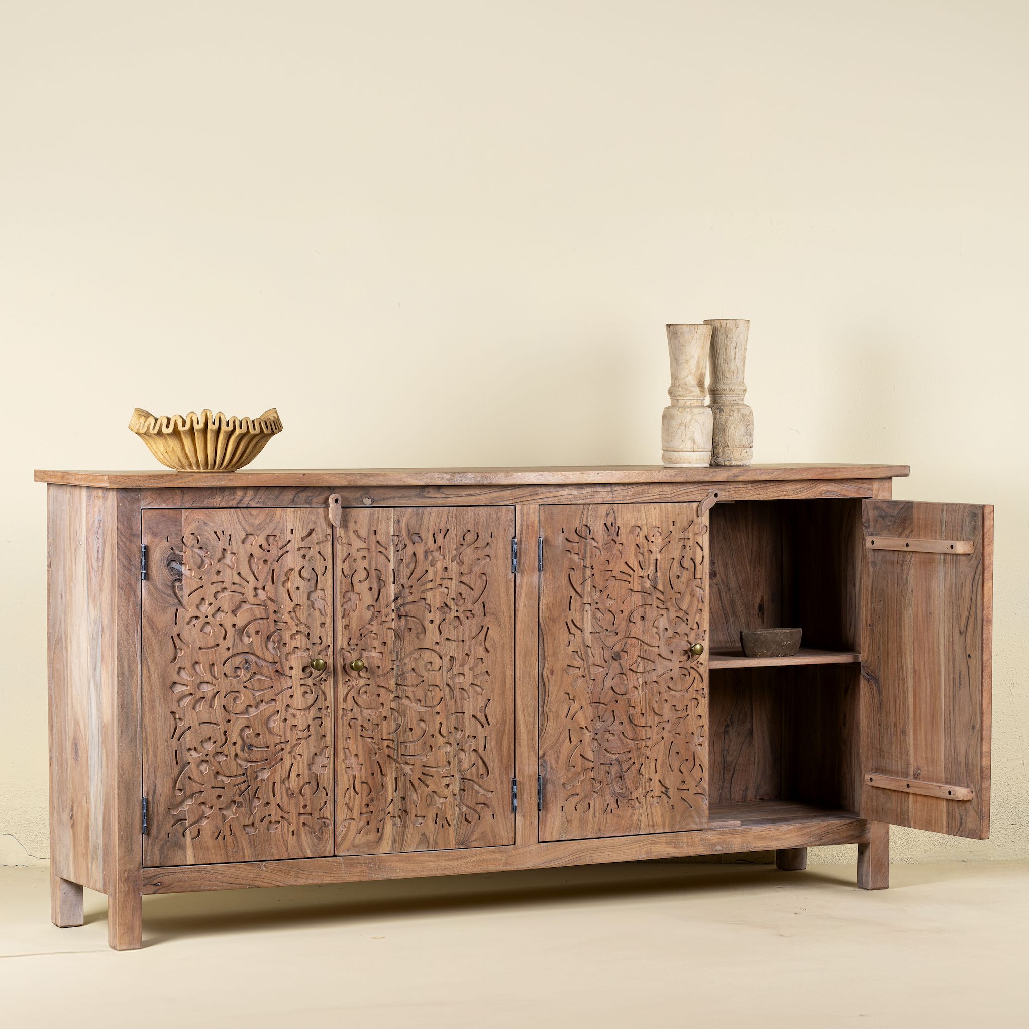 Open door picture of an acacia wood sideboard with floral carvings over all 4 doors and brass fitted door handles.