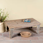 Side angle image of a sandblasted reclaimed teak wood coffee table with carved antique Indian door top; unique teak wood furniture and living room furniture, 140 × 40 × 48 cm.