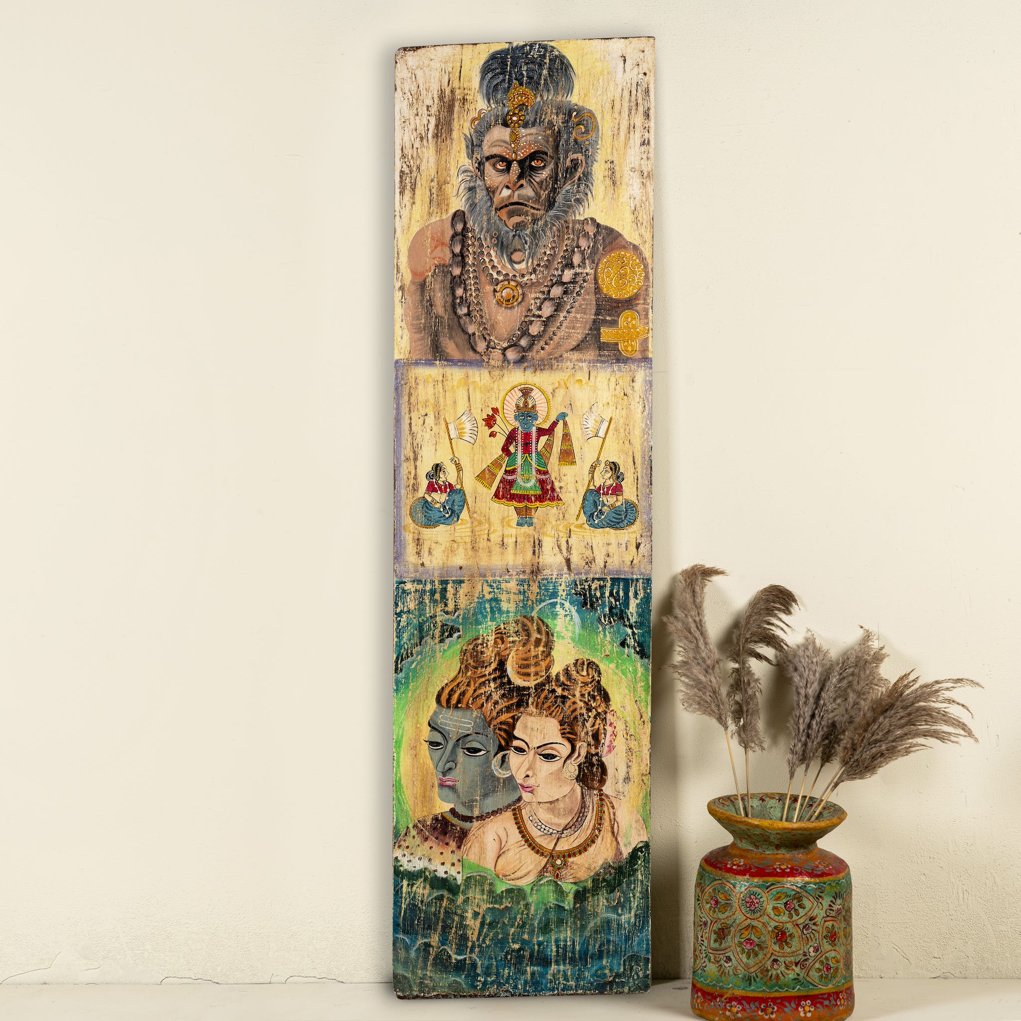 Hand-painted vintage door panel measuring 52x3x152 cm, featuring detailed depictions of Hindu deities—Hanuman at the top, a divine scene with attendants in the center, and a serene portrayal of Lord Shiva with Parvati at the bottom—rendered on distressed wood for a timeworn, sacred aesthetic.
