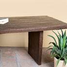 Close up image of a rustic reclaimed wood log dining table with block legs, sustainable furniture design, 240×100×75 cm.