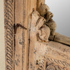 Close up of a hand-carved mirror crafted from an old teak wood window frame, featuring intricate floral and scrollwork details with a natural distressed finish and an arched top design reflecting traditional Indian craftsmanship.

