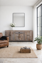 Lifestyle imagination of a reclaimed wood sideboard Devina in rustic minimalistic style with cabinet doors and central drawer. A sustainable furniture piece showcasing natural wood grain and timeless simplicity.