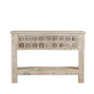 White background image of a hand carved console table made from reclaimed teak wood, featuring a detailed front panel with geometric floral motifs and a distressed whitewashed finish, complemented by a lower shelf for added storage or display.
 