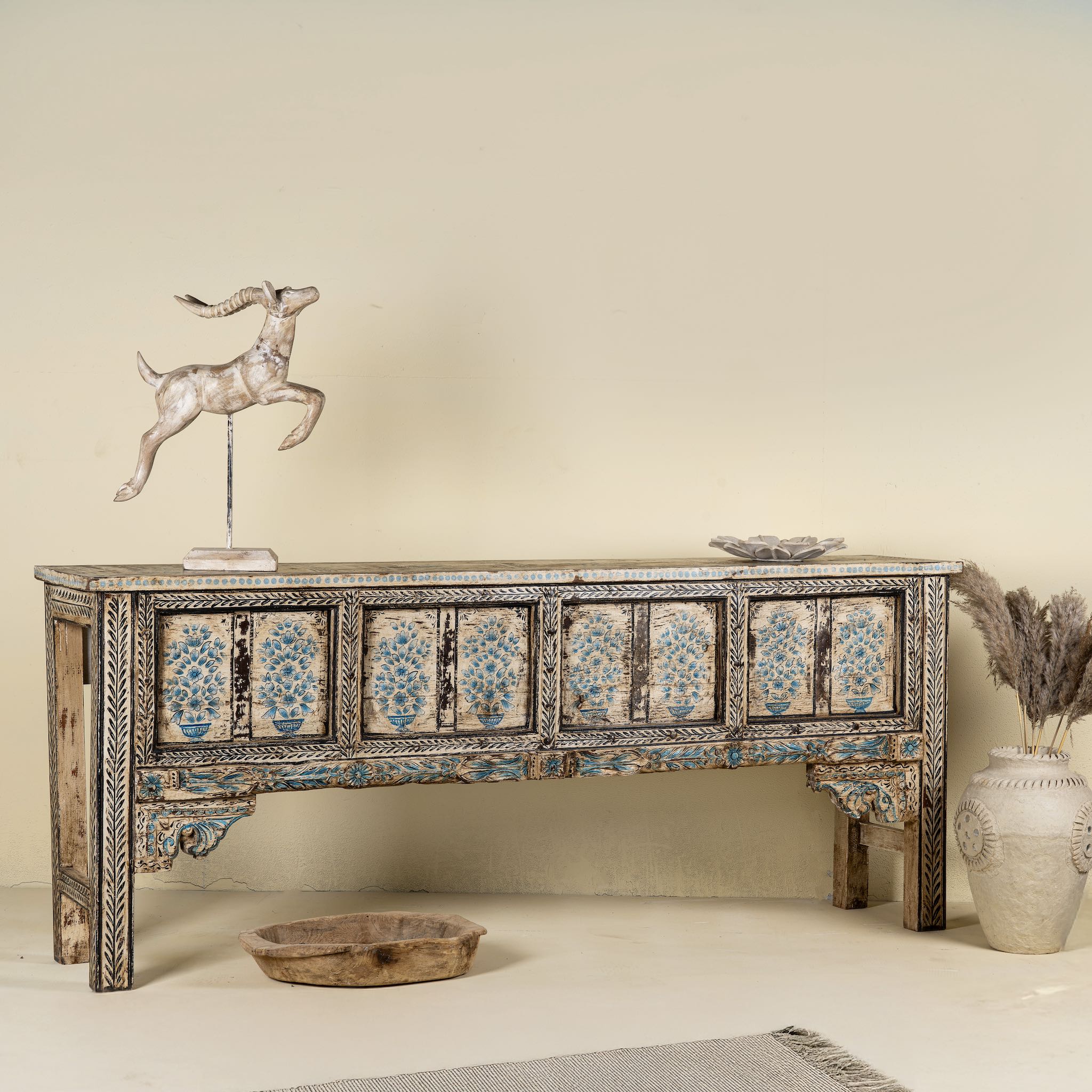 Side angle image of a hand painted console table in reclaimed teak with floral motifs and antique distressed finish, 197 × 40 × 82 cm.