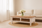 Lifestyle imagination of a hand carved mango wood coffee table with floral frame detailing; rustic natural finish, 140 × 90 × 46 cm.