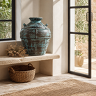 Lifestyle image of a hand-painted clay vase with vintage distressed turquoise finish, sculptural side handles and decorative rivet details, 30x38cm.