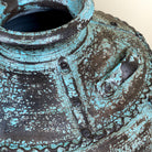 Close up image of a hand-painted clay vase with vintage distressed turquoise finish, sculptural side handles and decorative rivet details, 30x38cm.