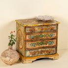 Side angle image of a hand-painted reclaimed wood chest of drawers with floral designs and distressed antique finish; perfect for bohemian interiors and vintage hand painted furniture lovers.