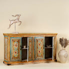 Side angle image with open doors of a hand painted wooden dresser with floral and geometric motifs, reclaimed wood living room furniture in vintage boho style, 170 × 45 × 95 cm.