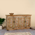 Side angle image of a hand painted wooden dresser with floral and geometric motifs, reclaimed wood living room furniture in vintage boho style, 170 × 45 × 95 cm.