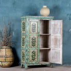 Open door view of a vintage cabinet made from reclaimed wood, featuring hand-painted floral and tree motifs in vibrant green, red, and turquoise tones for a joyful, artistic touch.