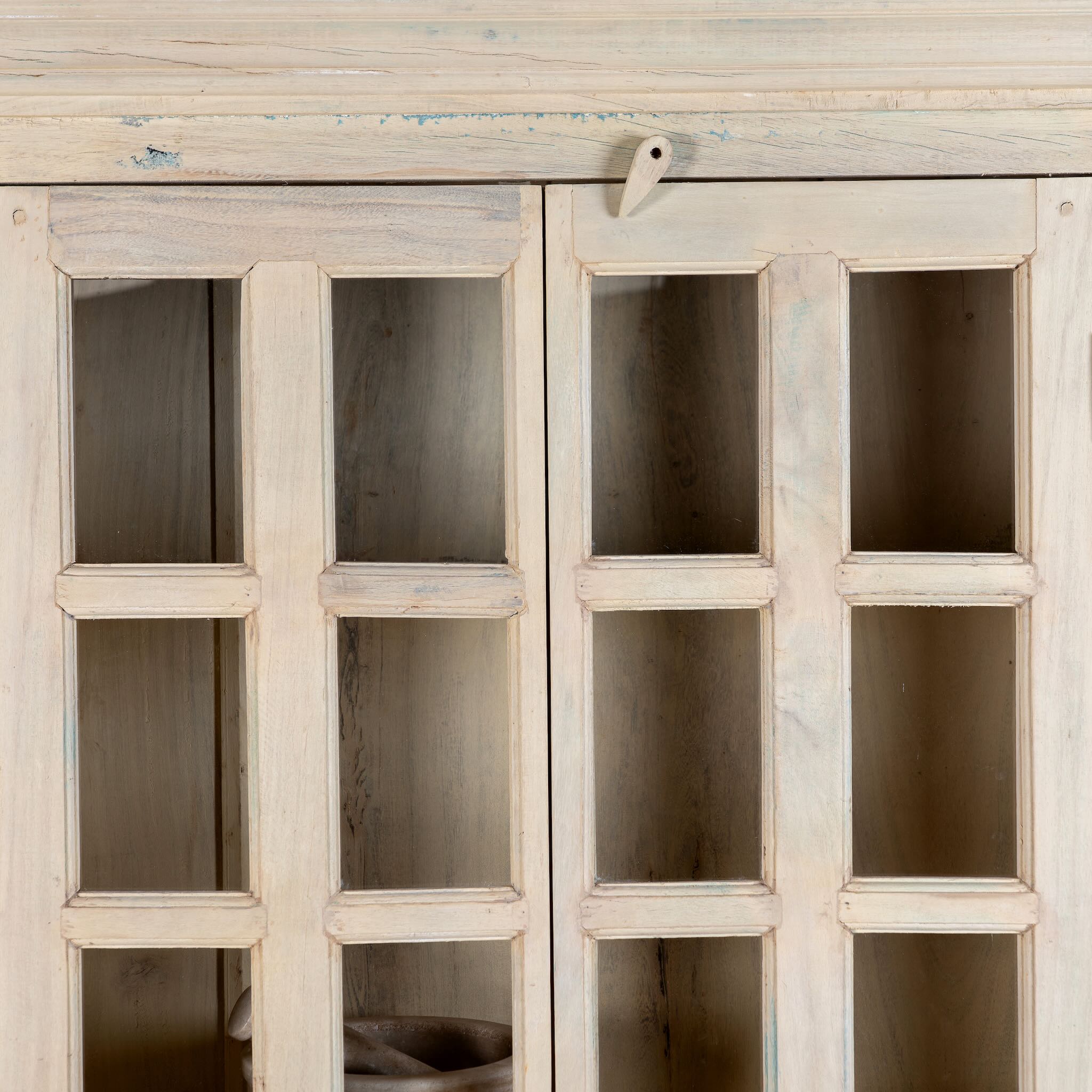 Close up image of a reclaimed wood display cabinet Eknoor with glass-panelled doors and natural weathered finish. Sustainable living room furniture that can also function as a reclaimed wood wardrobe with spacious shelving.