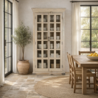 Lifestyle image of a reclaimed wood display cabinet Eknoor with glass-panelled doors and natural weathered finish. Sustainable living room furniture that can also function as a reclaimed wood wardrobe with spacious shelving.