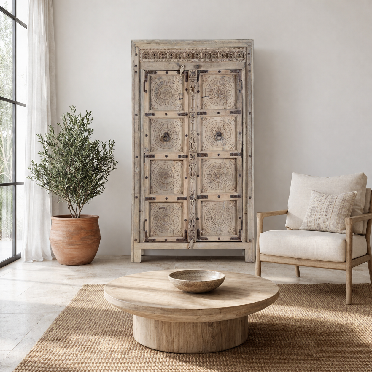 Lifestyle image of a reclaimed teak wood cabinet Elayna featuring an antique Indian door with carved motifs and iron accents. A unique piece of old door furniture in Mediterranean style, offering practical storage and historic charm.